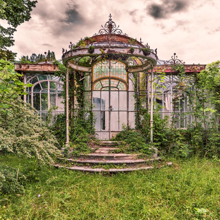 Verrostetes Glas Garten Pavillion mit Grünpflanzen überwachsen. Rusty glass garden pavilion overgrown with green plants.